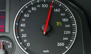 Tacho zeigt 100 km/h. Die gelbe Warnleuchte mit Uhr deutet auf eine mögliche Tacho-Toleranz oder Geschwindigkeitsbegrenzung hin.