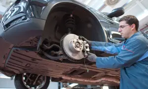 Mechaniker prüft Bremsen eines Autos. Das Quietschen der Bremsen kurz vor Stillstand ist ein Warnsignal für Verschleiß.