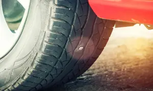 Ein Nagel steckt im Reifen. Das Auto hat einen Platten.
