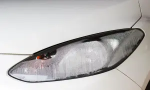 Kleine Wassertropfen bilden einen Schleier auf dem Scheinwerferglas, was auf Feuchtigkeit im Scheinwerfer hindeutet.