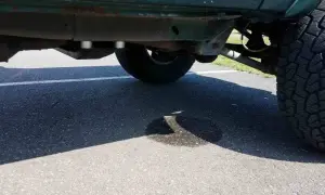 Ein Auto tropft Wasser nach der Fahrt. Eine Pfütze bildet sich auf dem Asphalt unter dem Fahrzeug.