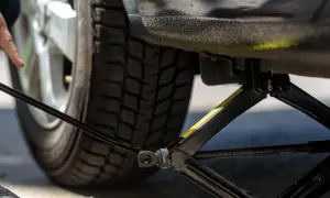 Mann hebt das Auto mit einem Wagenheber an, um neue Reifen einzufahren.