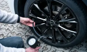 Person pumpt Reifen auf, um den Felgenschutz bei Reifen zu gewährleisten. Der schwarze Alufelge ist glänzend.