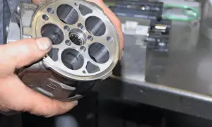 Hände halten einen Klimakompressor zur Überprüfung, ob die Magnetkupplung gewechselt werden muss.