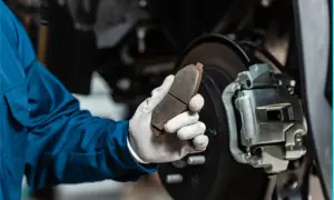 Mechaniker hält abgefahrene Bremsen in der Hand, bereit für den Austausch.