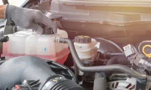 Hand in glove checks the coolant level in the car's engine. The pink liquid is the **wasser unter auto**, essential for keeping the engine cool.