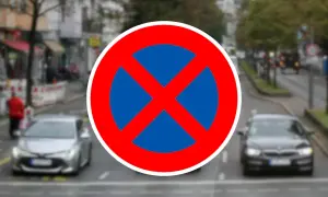 Verkehrsschild "Absolutes Halteverbot". Parken im absoluten Halteverbot strafe droht. Autos fahren auf einer Straße.