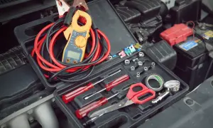 Werkzeugkasten mit Zangenamperemeter, Kabeln und Werkzeugen, bereit, die 12V Batterie zu messen.