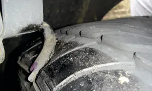 Nahaufnahme eines Reifens mit sichtbaren Rissen und einer verbogenen Metallfeder. Ein **feder gebrochen auto**-Problem, das dringend behoben werden muss.