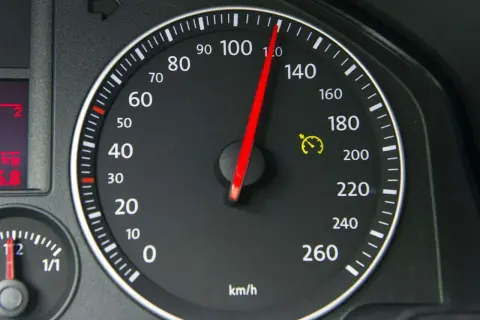 Tacho zeigt 100 km/h. Die gelbe Warnleuchte mit Uhr deutet auf eine mögliche Tacho-Toleranz oder Geschwindigkeitsbegrenzung hin.