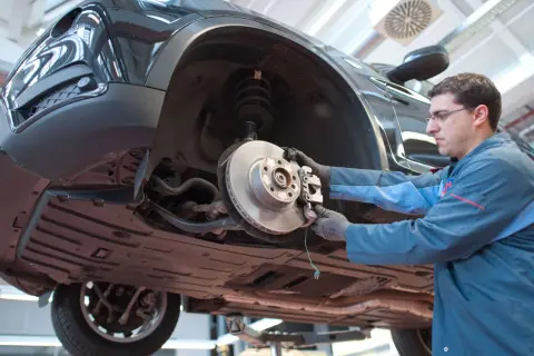 Mechaniker prüft Bremsen eines Autos. Das Quietschen der Bremsen kurz vor Stillstand ist ein Warnsignal für Verschleiß.