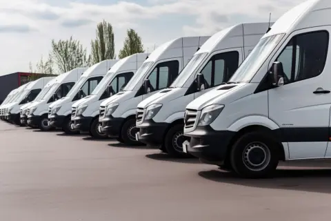 Reihe weißer Lieferwagen, bereit für den Transport. Ein Montagefahrzeug mit nach Hause nehmen ist ein Traum für viele.