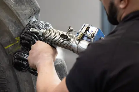 Ein Mechaniker repariert einen Reifen mit einem Vulkanisationsgerät. Die Hitze schmilzt das Gummi, um den Schaden zu beheben.