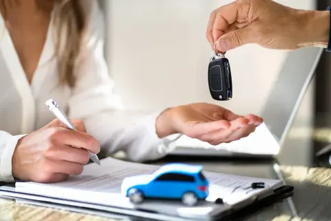 Schlüsselübergabe für ein neues Auto. Der neue Fahrzeughalter unterschreibt den Fahrzeugschein.