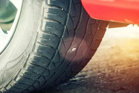 Ein Nagel steckt im Reifen. Das Auto hat einen Platten.