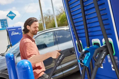 Mann lädt E-Auto an Aral Pulse Ladesäule. Ein Nutzungsvertrag Kfz gewerblich ist hierfür nötig.