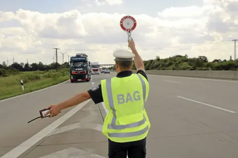BAG-Kontrolleur regelt den Verkehr auf der Autobahn. LKW werden angehalten.