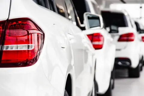 Reihe weißer Autos, bereit, als Poolfahrzeug mit nach Hause genommen zu werden.