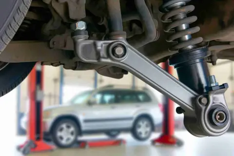 Auto-Aufhängung mit defektem Querlenker. Symptome wie Klappern oder schlechte Straßenlage deuten auf Probleme hin.
