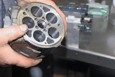 Hände halten einen Klimakompressor zur Überprüfung, ob die Magnetkupplung gewechselt werden muss.