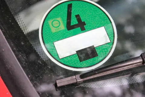 Grüne Umweltplakette mit der Nummer 4, die zeigt, dass das Fahrzeug die Kriterien für die Umweltzone erfüllt. Die Feinstaubplakette anbringen ist wichtig für die Einfahrt in viele Städte.