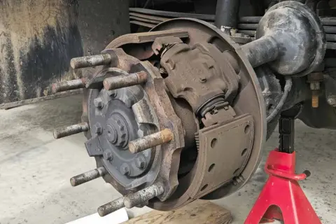 Detailaufnahme einer Trommelbremse mit freiliegenden Bremsbelägen und Radbolzen. Die Handbremse einstellen erfordert hier präzises Arbeiten.