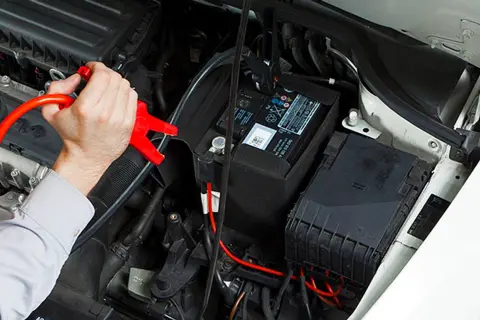 Mann schließt Starthilfekabel an EFB Batterie an, um sie zu laden.