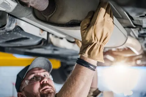 Mechaniker prüft Auspuffanlage. Ein kaputter Katalysator kann das Weiterfahren erschweren.