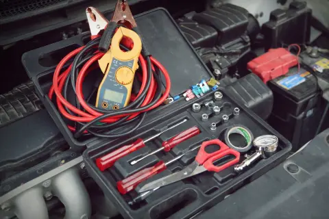 Werkzeugkasten mit Zangenamperemeter, Kabeln und Werkzeugen, bereit, die 12V Batterie zu messen.