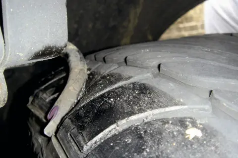 Nahaufnahme eines Reifens mit sichtbaren Rissen und einer verbogenen Metallfeder. Ein **feder gebrochen auto**-Problem, das dringend behoben werden muss.