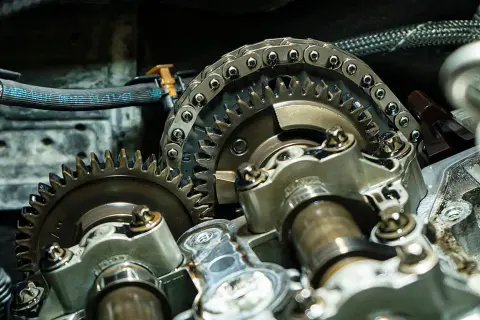 Nahaufnahme eines Motors mit Zahnrädern und Steuerkette. Ein Mechaniker prüft, wann steuerkette wechseln.
