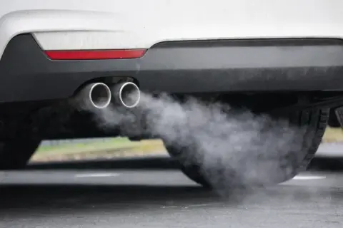 Ein Auto im Leerlauf stößt Rauch aus seinen zwei Auspuffrohren aus.