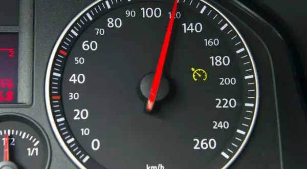 Tacho zeigt 100 km/h. Die gelbe Warnleuchte mit Uhr deutet auf eine mögliche Tacho-Toleranz oder Geschwindigkeitsbegrenzung hin.