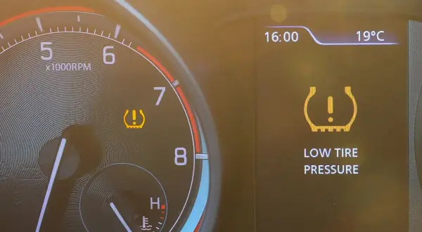 Warnleuchte für **druckverlust reifen** leuchtet auf dem Armaturenbrett. Die Anzeige zeigt "LOW TIRE PRESSURE".