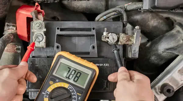 Hände prüfen mit Multimeter die Spannung der Autobatterie, um zu sehen, ob sie bereit ist, die Batterie zu laden.