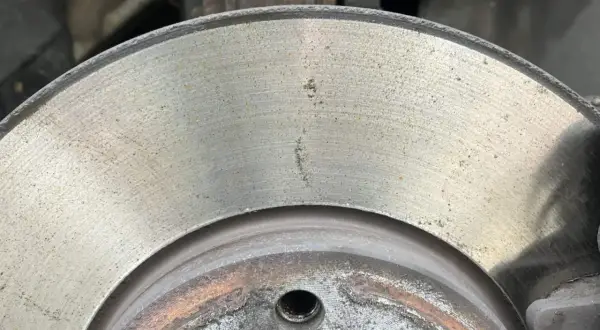 Nahaufnahme einer Bremsscheibe mit leichtem Rost. Die Oberfläche zeigt feine Rillen und einige gelbliche Spuren, die auf beginnenden Rost hindeuten.