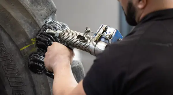 Ein Mechaniker repariert einen Reifen mit einem Vulkanisationsgerät. Die Hitze schmilzt das Gummi, um den Schaden zu beheben.