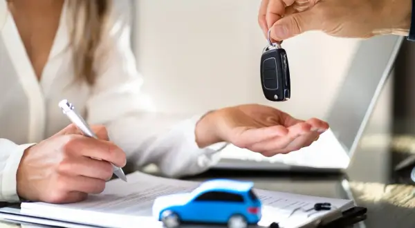 Schlüsselübergabe für ein neues Auto. Der neue Fahrzeughalter unterschreibt den Fahrzeugschein.