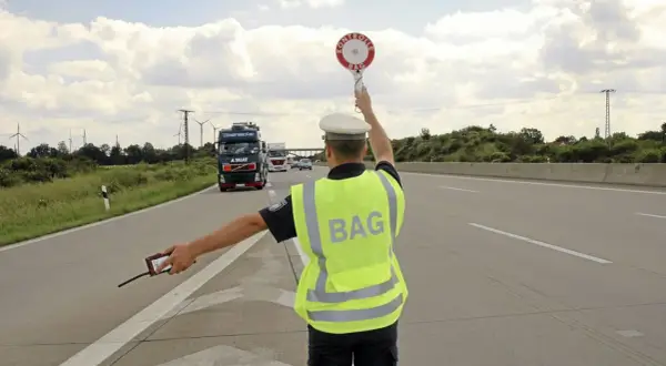 BAG-Kontrolleur regelt den Verkehr auf der Autobahn. LKW werden angehalten.