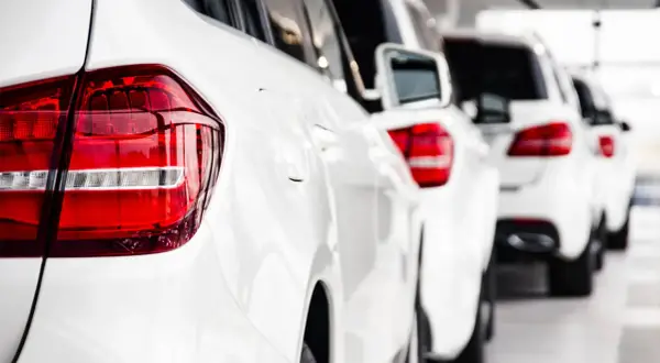 Reihe weißer Autos, bereit, als Poolfahrzeug mit nach Hause genommen zu werden.