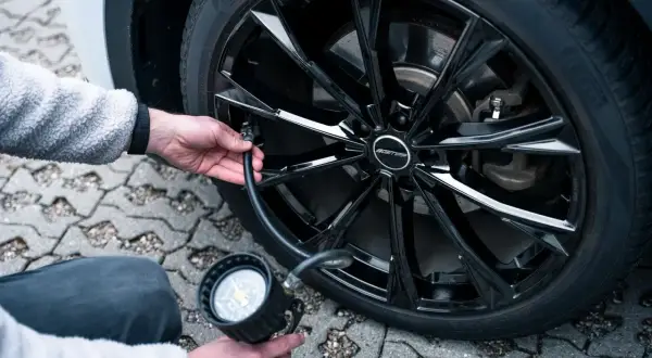 Person pumpt Reifen auf, um den Felgenschutz bei Reifen zu gewährleisten. Der schwarze Alufelge ist glänzend.
