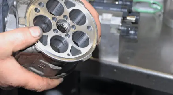 Hände halten einen Klimakompressor zur Überprüfung, ob die Magnetkupplung gewechselt werden muss.