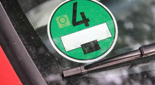 Grüne Umweltplakette mit der Nummer 4, die zeigt, dass das Fahrzeug die Kriterien für die Umweltzone erfüllt. Die Feinstaubplakette anbringen ist wichtig für die Einfahrt in viele Städte.