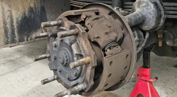 Detailaufnahme einer Trommelbremse mit freiliegenden Bremsbelägen und Radbolzen. Die Handbremse einstellen erfordert hier präzises Arbeiten.
