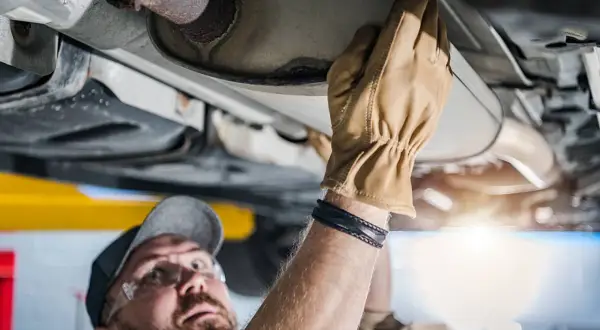 Mechaniker prüft Auspuffanlage. Ein kaputter Katalysator kann das Weiterfahren erschweren.