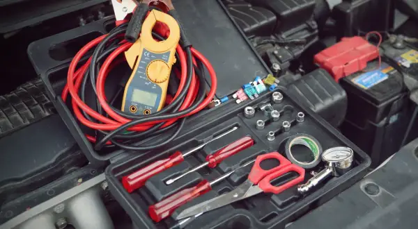 Werkzeugkasten mit Zangenamperemeter, Kabeln und Werkzeugen, bereit, die 12V Batterie zu messen.