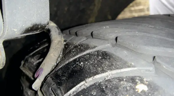 Nahaufnahme eines Reifens mit sichtbaren Rissen und einer verbogenen Metallfeder. Ein **feder gebrochen auto**-Problem, das dringend behoben werden muss.