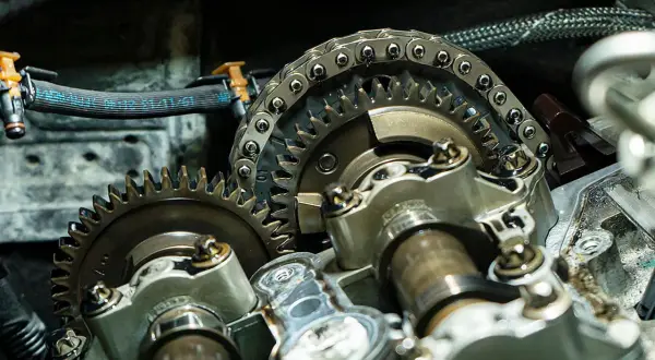 Nahaufnahme eines Motors mit Zahnrädern und Steuerkette. Ein Mechaniker prüft, wann steuerkette wechseln.