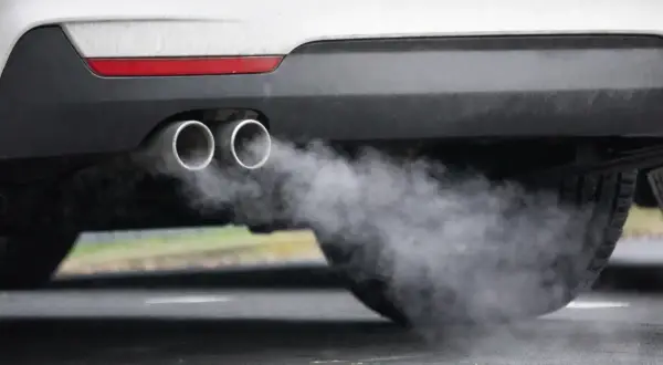 Ein Auto im Leerlauf stößt Rauch aus seinen zwei Auspuffrohren aus.