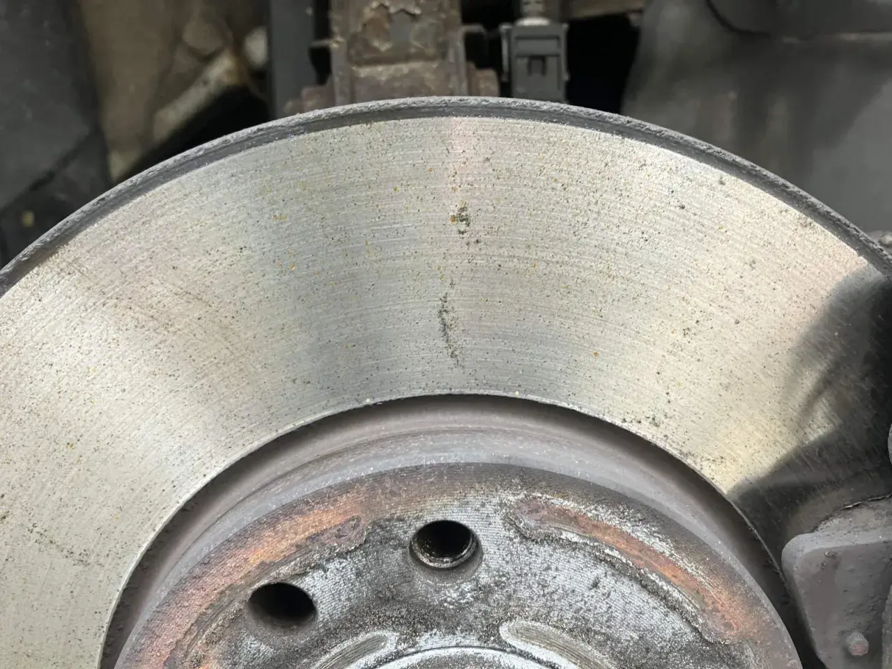 Nahaufnahme einer Bremsscheibe mit leichtem Rost. Die Oberfläche zeigt feine Rillen und einige gelbliche Spuren, die auf beginnenden Rost hindeuten.